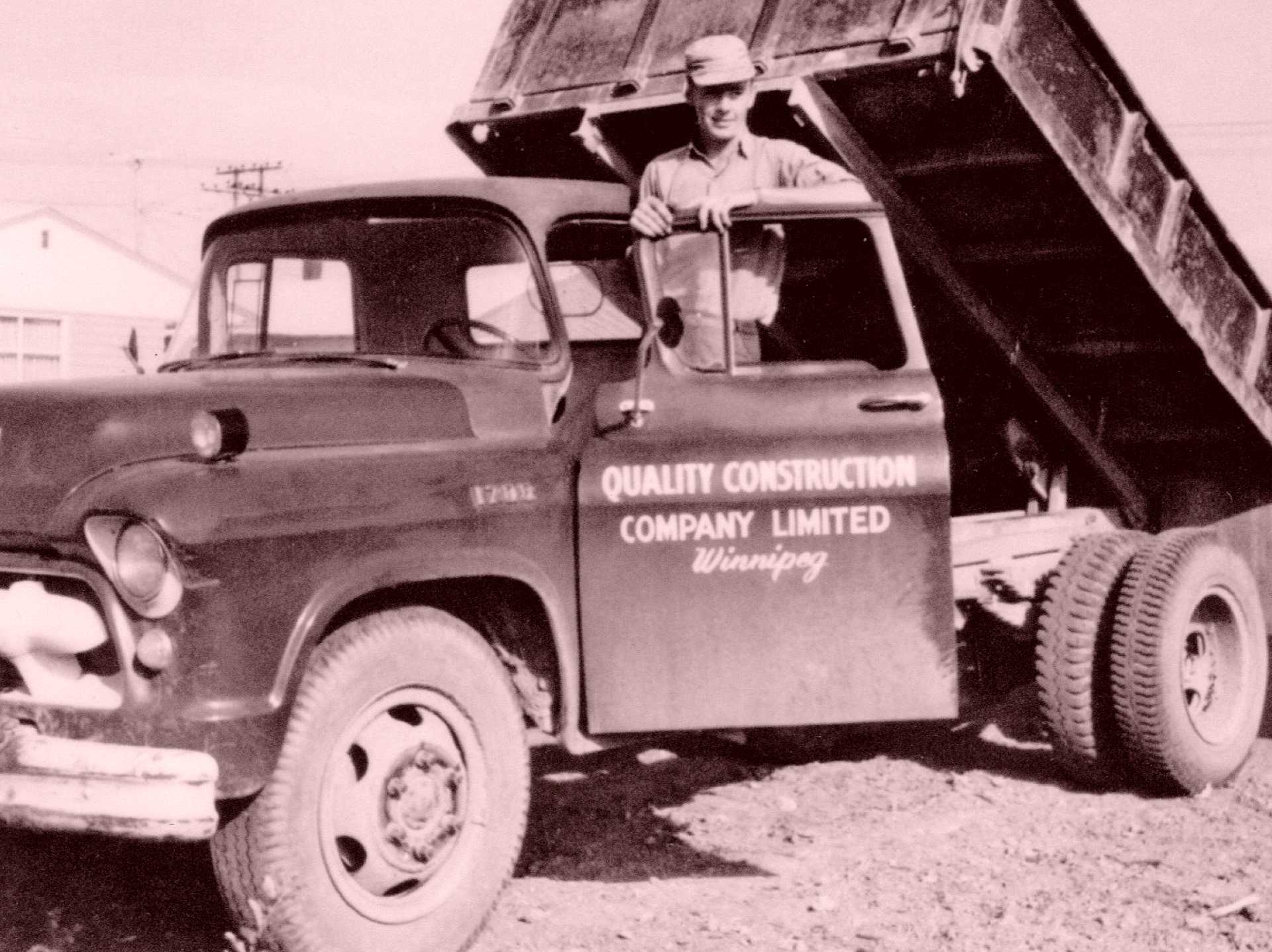 Founder leaning on a vintage Quality Construction Company Limited Winnipeg pickup truck